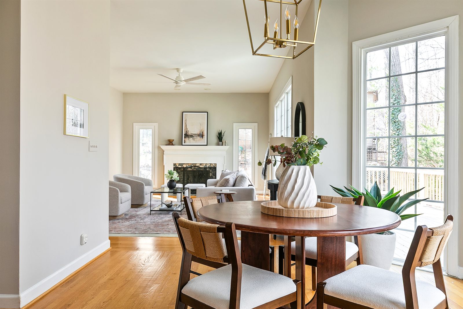 Staged breakfast nook with a round wood table, looking through to the living room and fireplace