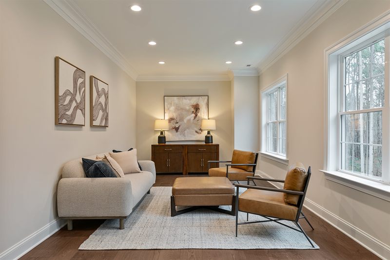 Living room with a cream sofa facing two tan leather chairs and a credenza with matching lamps