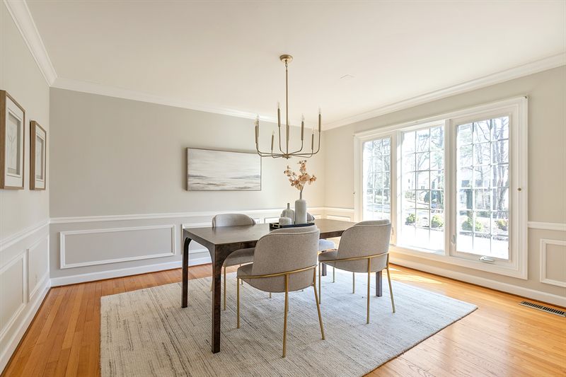 Dining room with a brass chandelier, wainscoting and French doors onto the garden