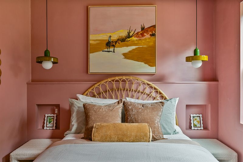 Arched rattan headboard against a terracotta wall, framed by two green glass sconces