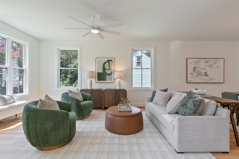 Living room with two green swivel chairs, a round leather ottoman and a cream sofa