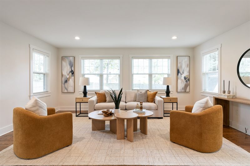 Living room with two caramel swivel chairs, nesting round coffee tables and a console under a mirror